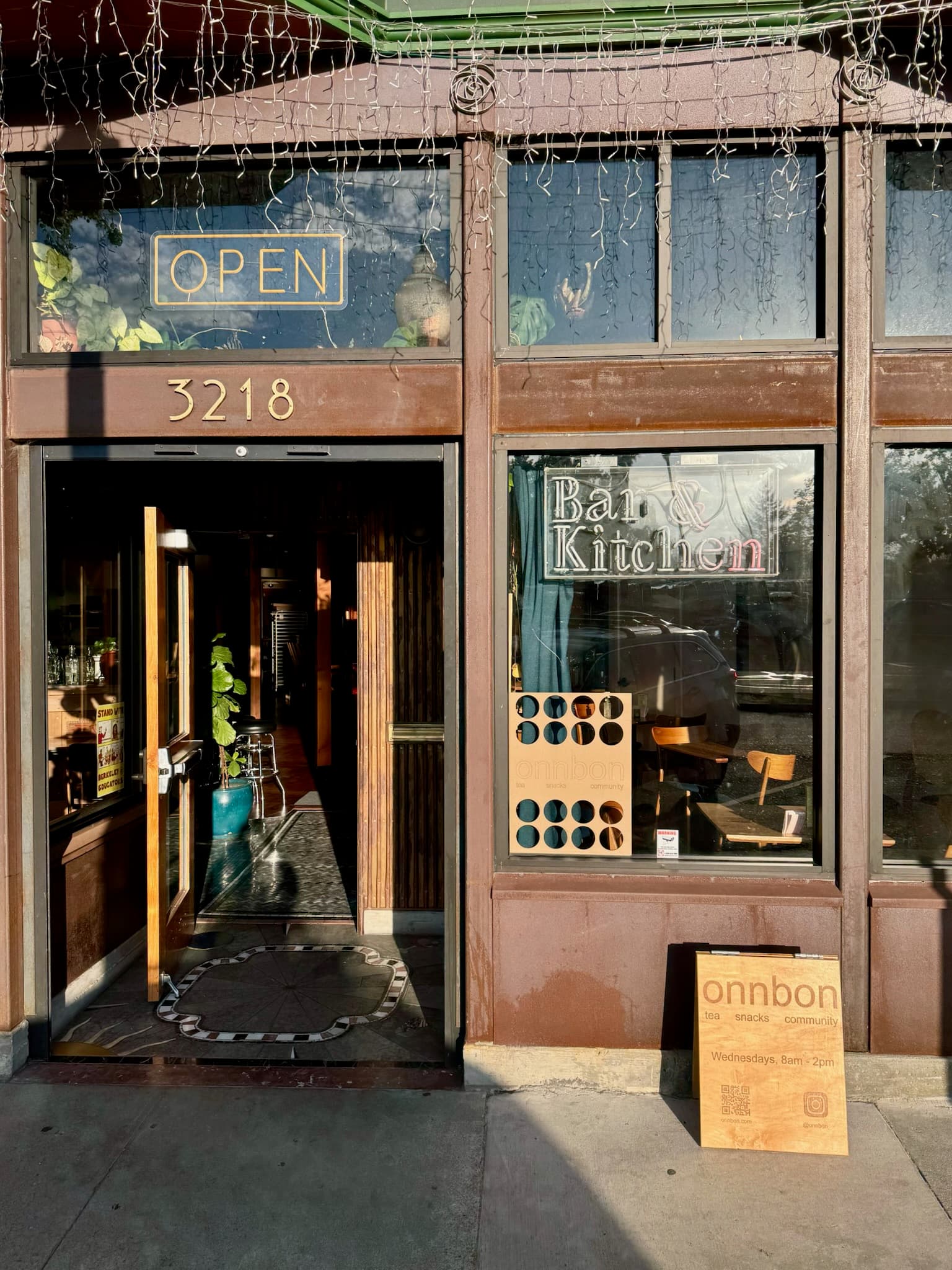 The open front door of Roses on Adeline, with onnbon popup signs in the window